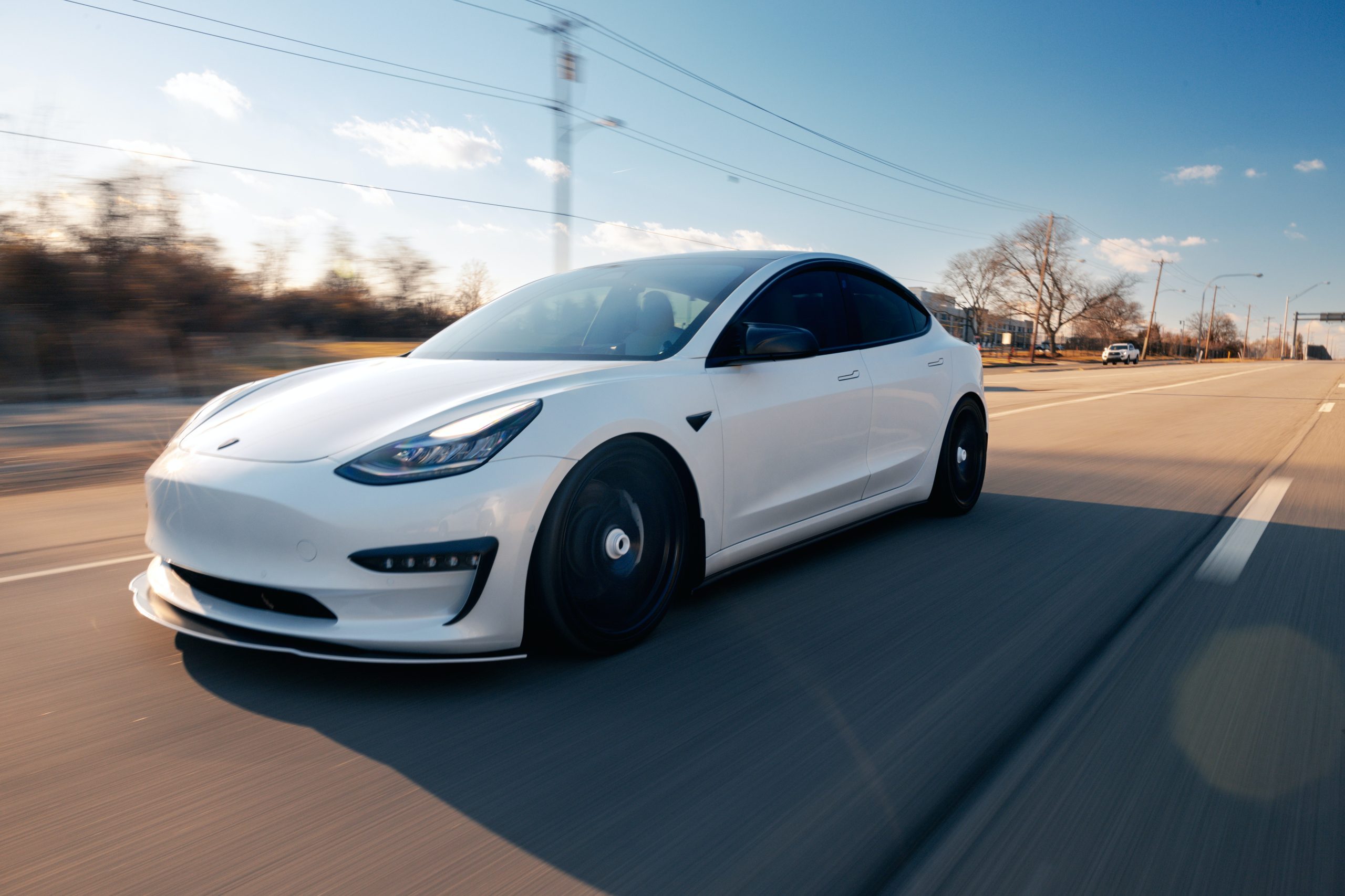 Witte Tesla model 3 rijdend op de baan